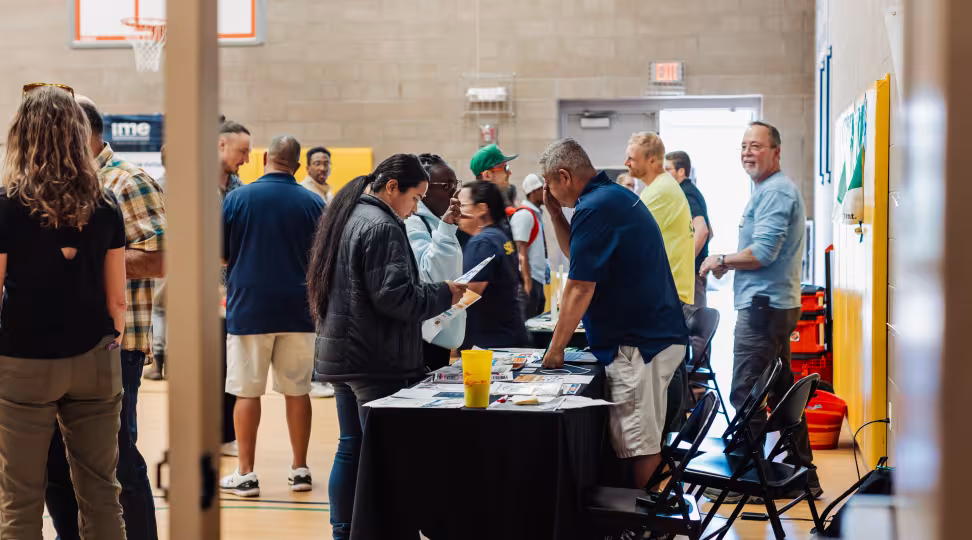 Attendees at an Electrification Workforce Network event getting information from experts at tables with informational materials