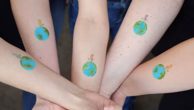 Arms outstretched with temporary tattoos of the Earth. 