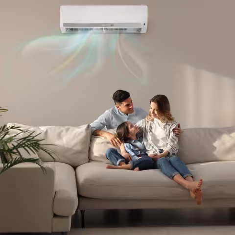 A family of three comfortably lounging on a couch with a mini split heat pump. Air flow from the heat pump is depicted with colored waves
