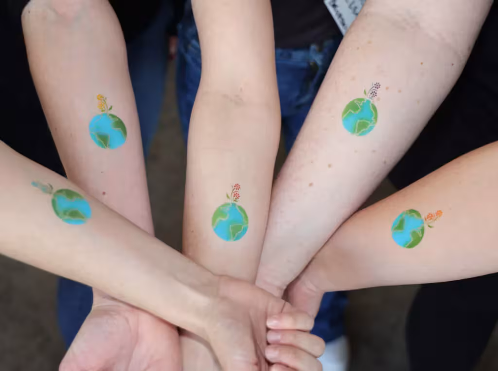 Arms outstretched with temporary tattoos of the Earth. 