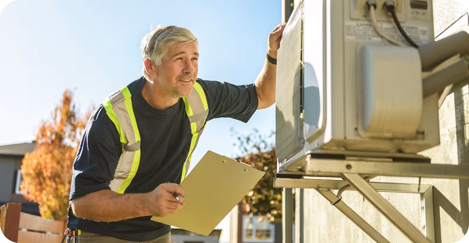 A man with a clipboard inspects a heat pump outside